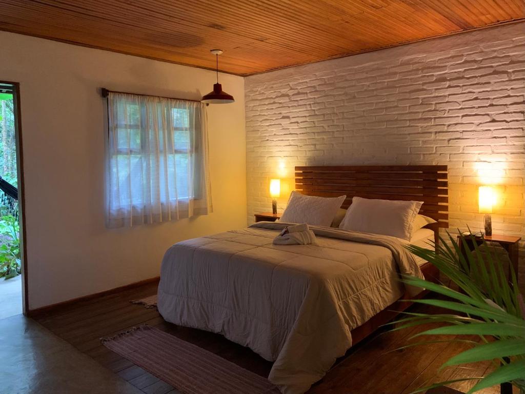 um quarto com uma cama grande e uma parede de tijolos em Pousada Sítio Itaúna em Penedo
