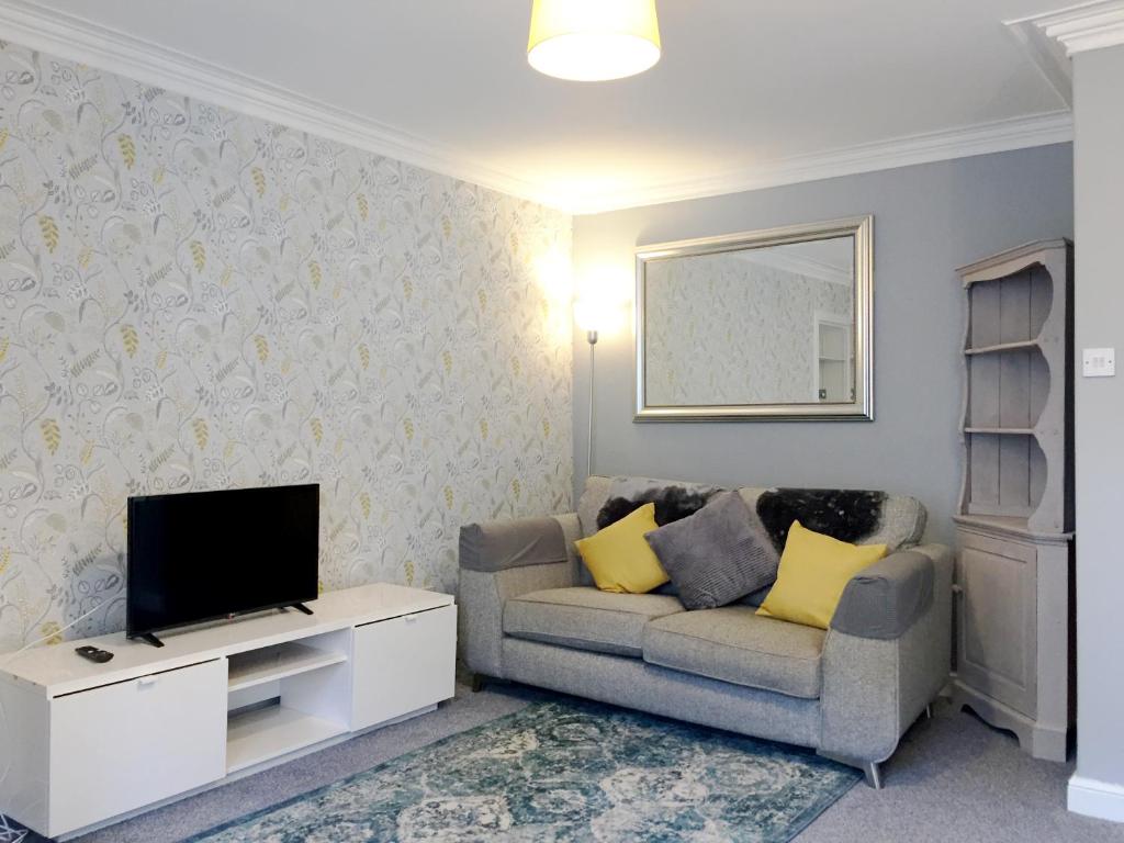 een woonkamer met een bank en een tv bij Dunbar Serviced Apartment in Dunbar