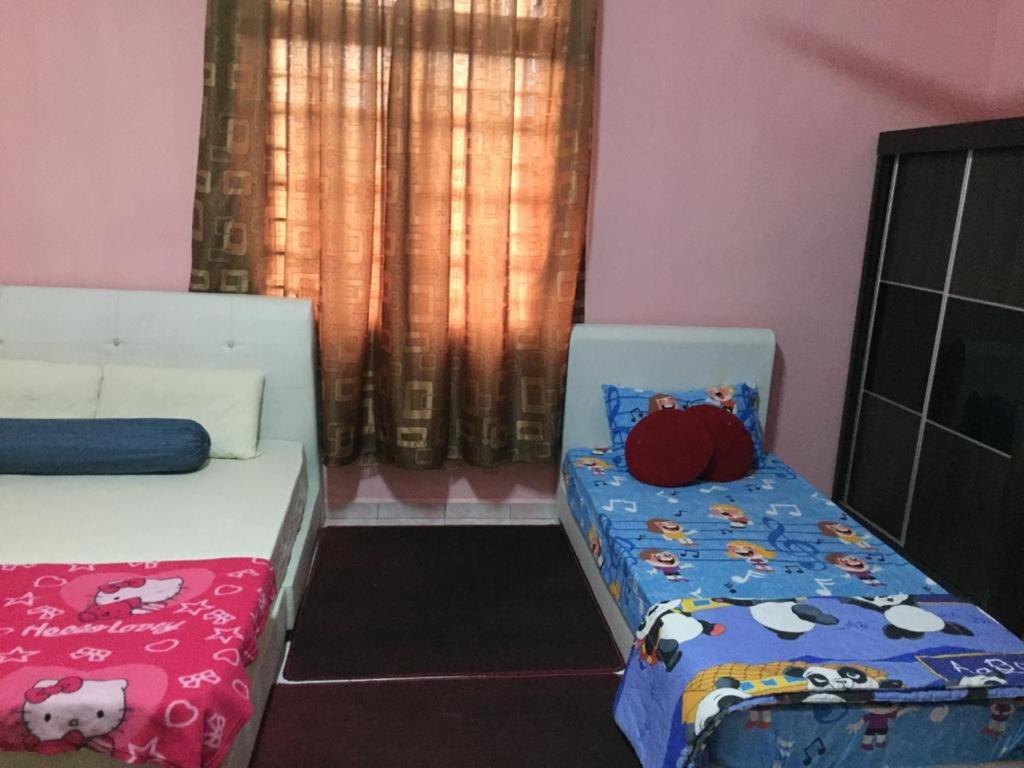 a bedroom with a bed and a crib with cow blanket at Guesthouse Adam in Pengkalan Cepa