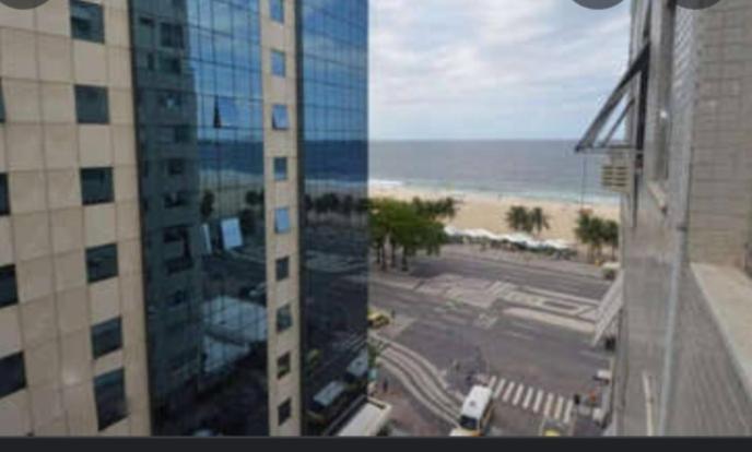 a view of a building with a beach and the ocean at Mar De Copacabana New Apartments in Rio de Janeiro