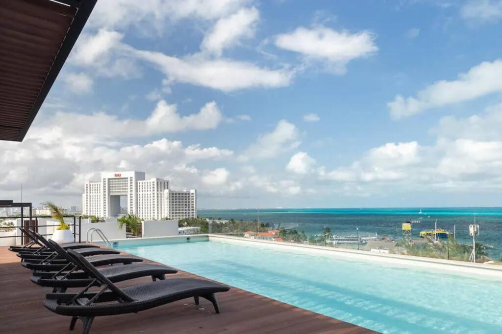 a swimming pool on the roof of a resort with the ocean at Beautiful room well located in the hotel zone of Cancun in Cancún