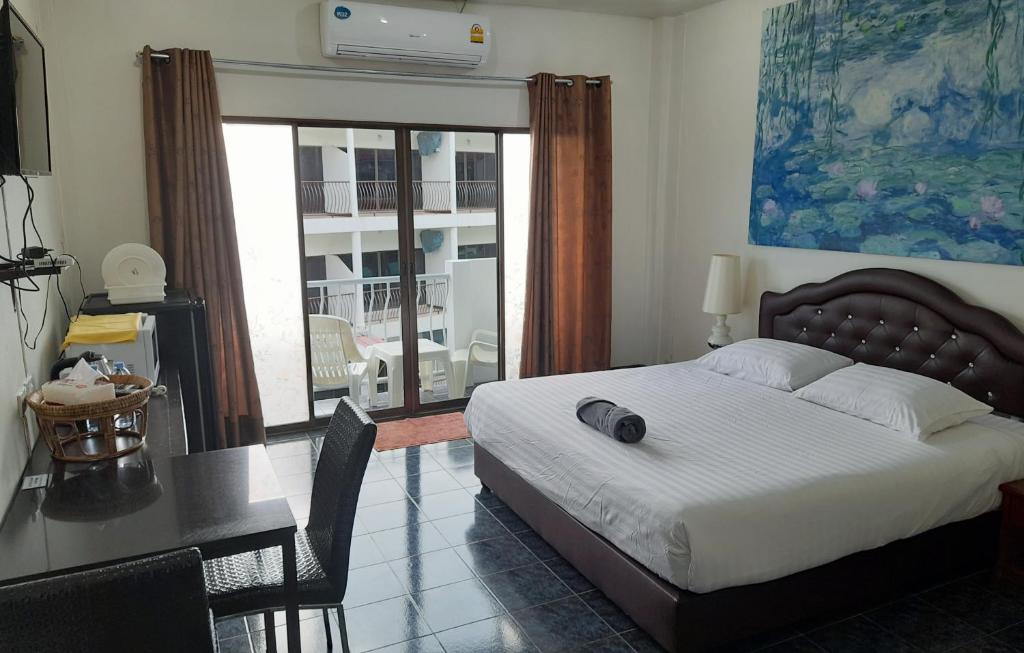 een slaapkamer met een bed en een bureau met een tafel en een bureau bij Sala Bua Room in Karon Beach