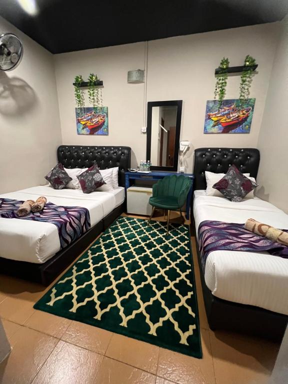 a room with three beds and a rug at Ghazrin's Garuda Hotel in Johor Bahru