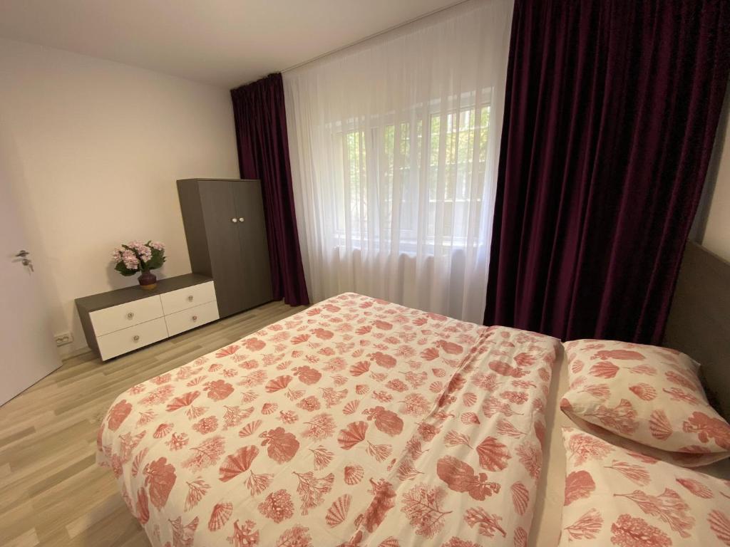 a bedroom with a bed and a window with curtains at Grove Apartment in Buzău
