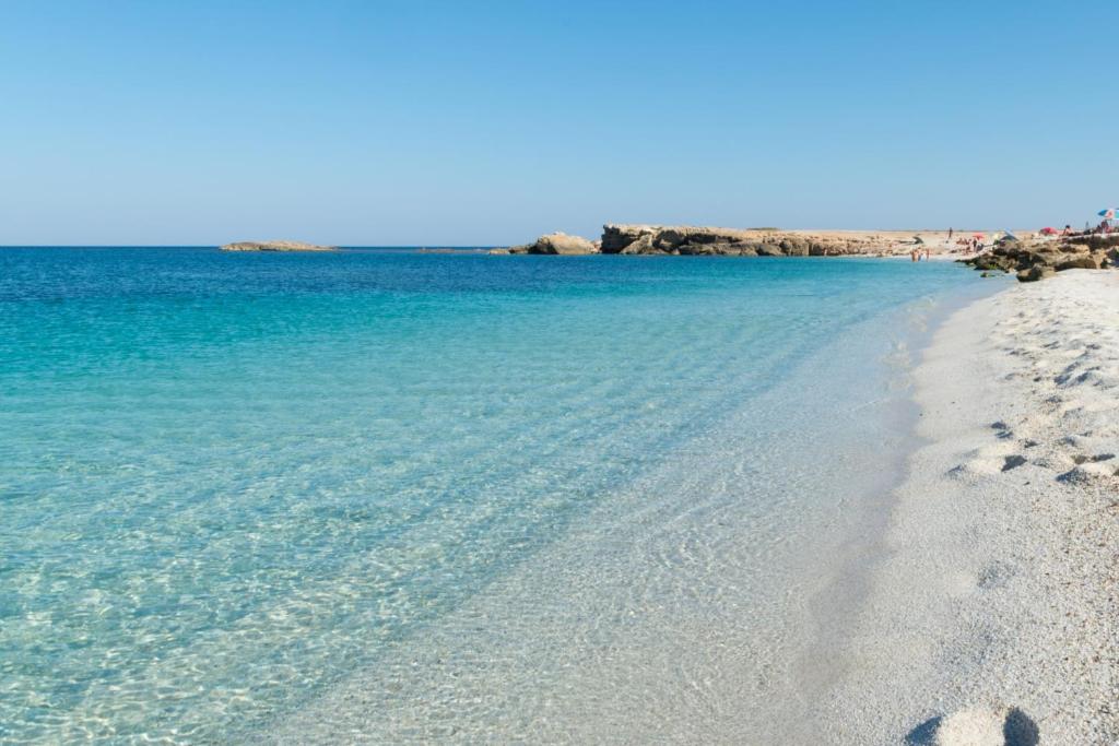 una spiaggia con acqua blu e impronte di piedi nella sabbia di Profumo di mare a Càbras