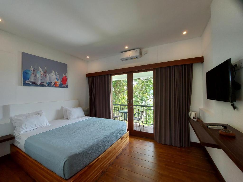 a bedroom with a bed and a balcony with a television at Marina Del Ray in Pelangan