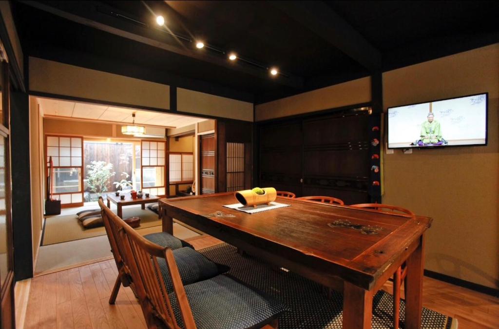 a dining room with a table and chairs and a television at 京町家の宿 三石 in Kyoto