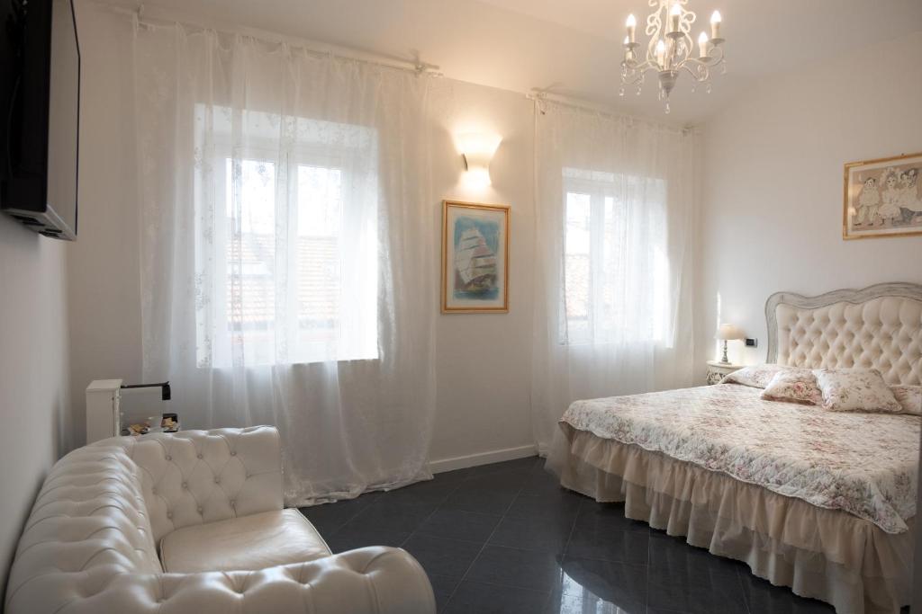 a white bedroom with a bed and a chair at Artemisia in Viareggio
