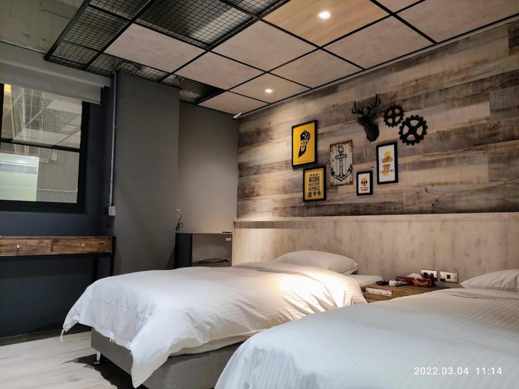 a bedroom with two beds and a wooden wall at 18世紀普魯士藍現代寓所Prussian Blue Inn工業風 in Kaohsiung