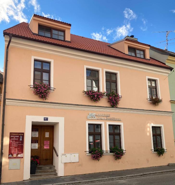 a building with flowers on the windows of it at Penzion a wellness U Třeboňské madony in Třeboň
