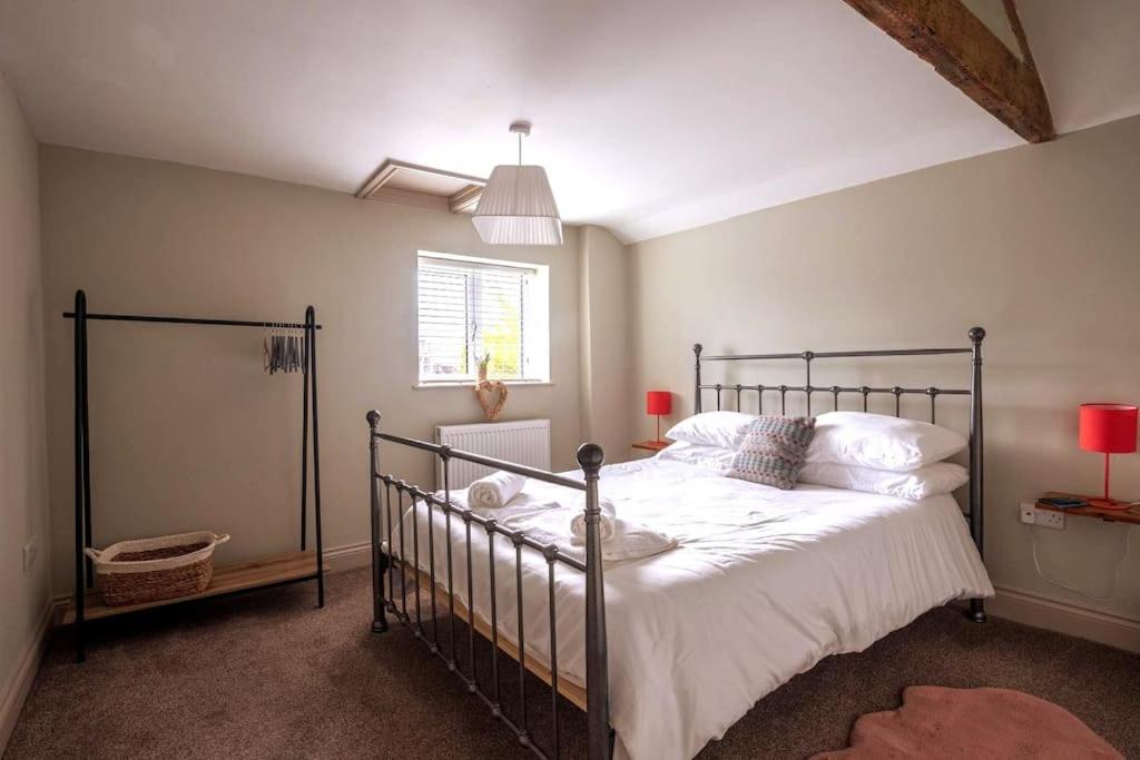 1 dormitorio con 1 cama con sábanas blancas y ventana en Y Cwtsh, en Llandeilo