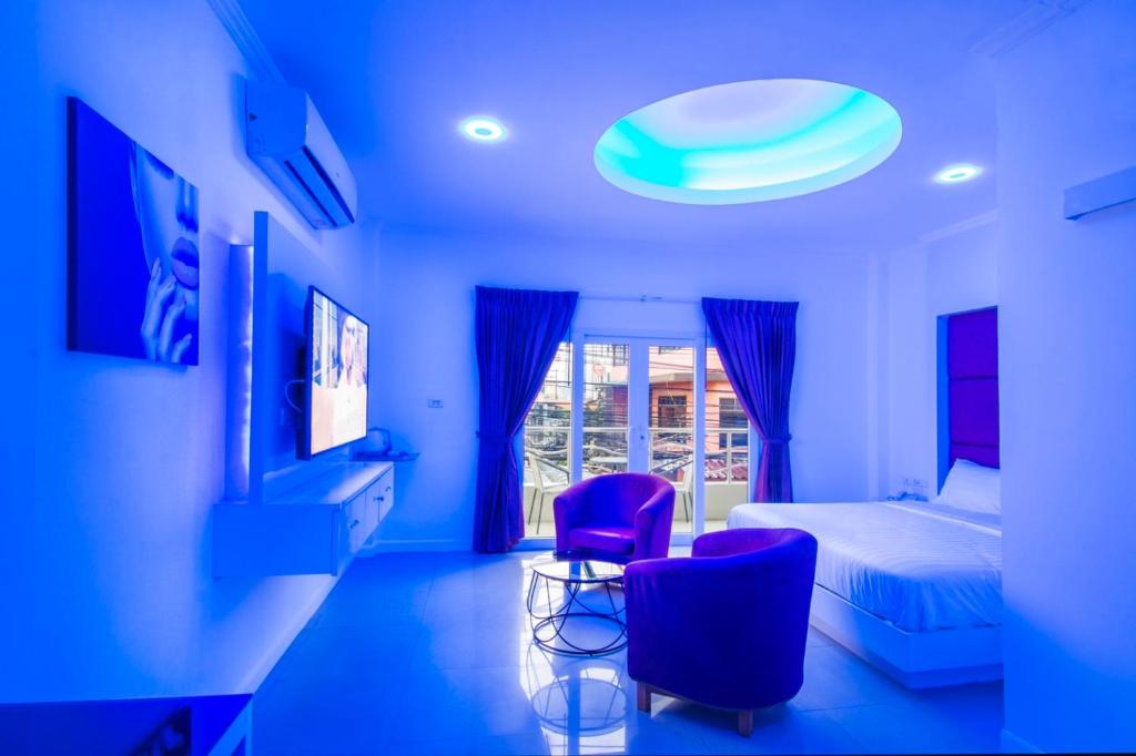 Habitación azul con 1 cama y 2 sillas moradas en titanic residence, en Pattaya central
