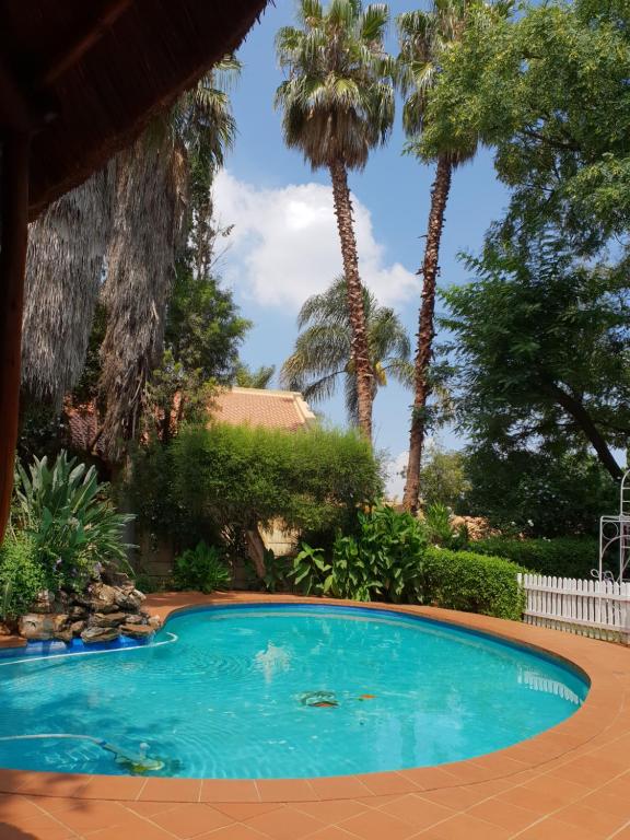 une piscine avec des palmiers en arrière-plan dans l'établissement "O Sole Mio" Self catering studio apartment in Bedfordview, à Bedfordview
