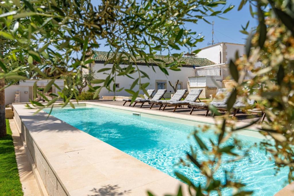 a swimming pool with two lounge chairs next to a house at Masseria dei Monaci in Otranto