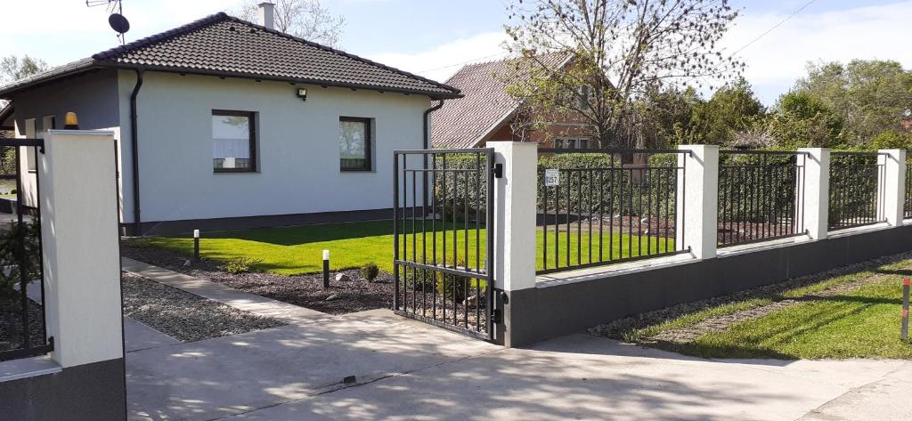 einen weißen Zaun vor einem Haus in der Unterkunft SunnySide nyaraló in Szarvas