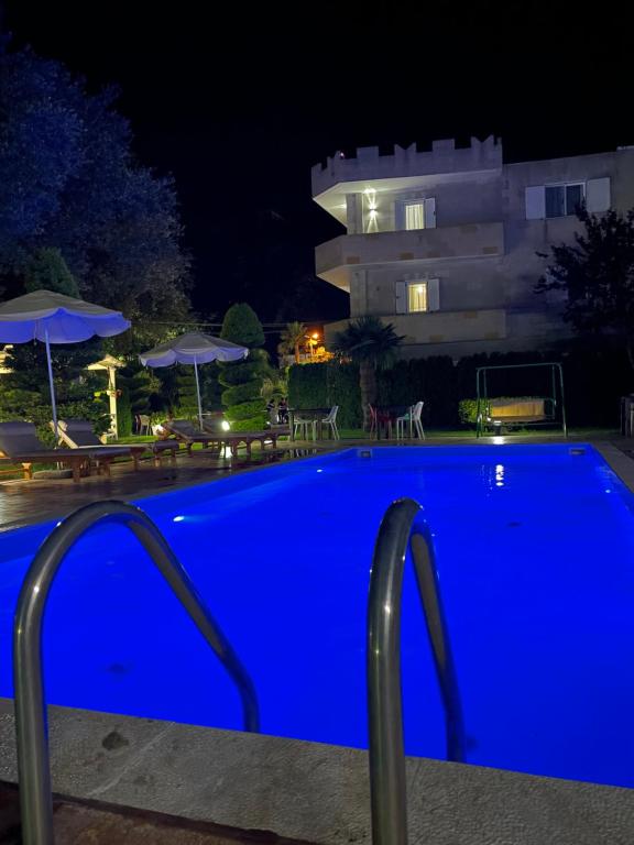 a blue swimming pool in front of a building at night at Vila Florika Hotel in Borsh