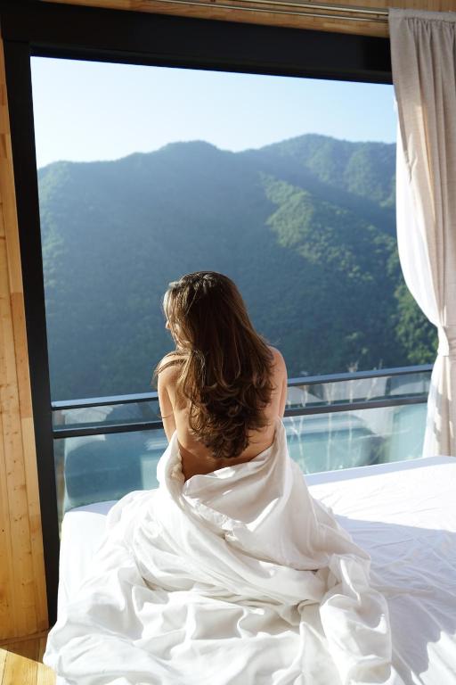 a woman sitting on a bed looking out a window at Pano Blueberry in Namlisevi