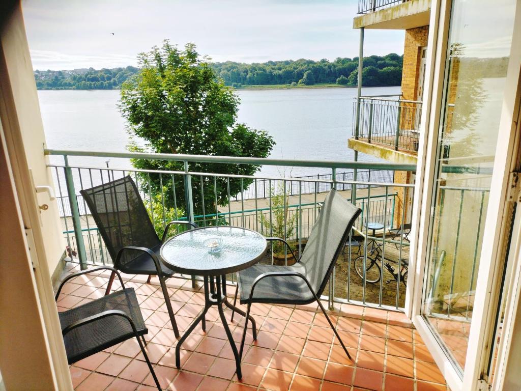 ロンドンデリーにあるDerry-Londonderry city centre waterfront appartmentの水辺の景色を望むバルコニー(テーブル、椅子付)