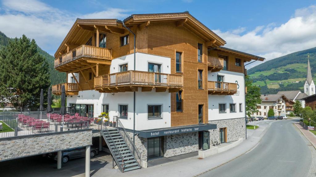 a large building with wooden balconies on a street at Herz3 Hotel Bar Restaurant Trattoria in Hollersbach im Pinzgau