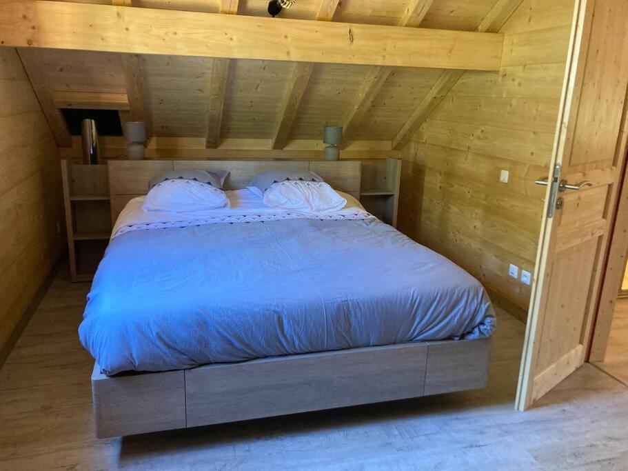 a bedroom with a bed in a wooden room at Forest Jura Lodge - Chalet des sapins in Alièze