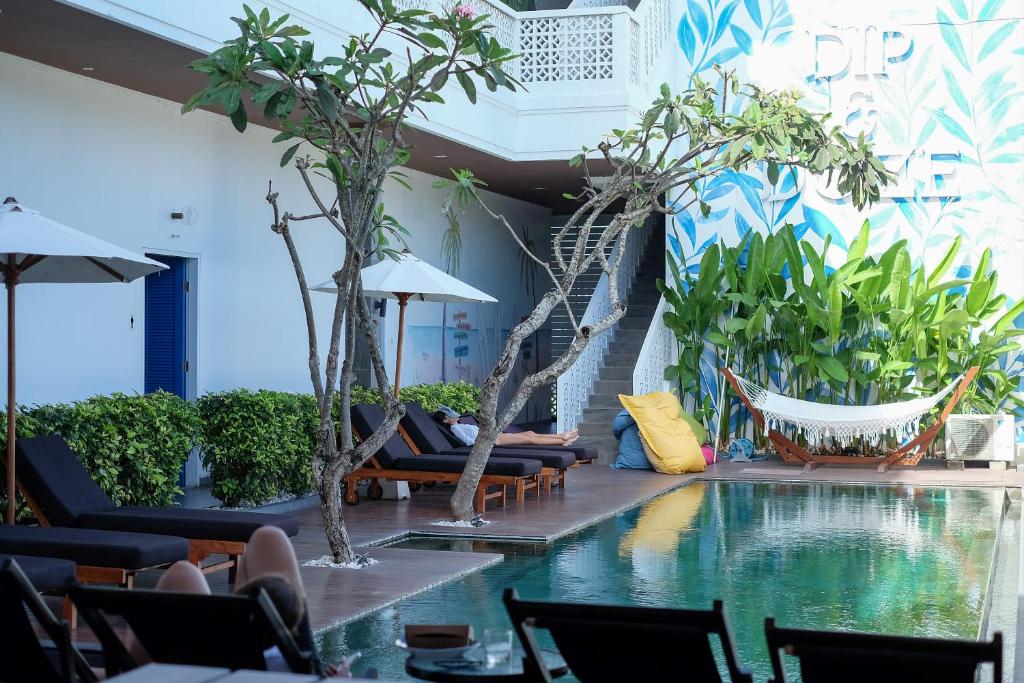 um átrio do hotel com piscina, cadeiras e árvores em Dip & Doze Boutique Hostel em Canggu