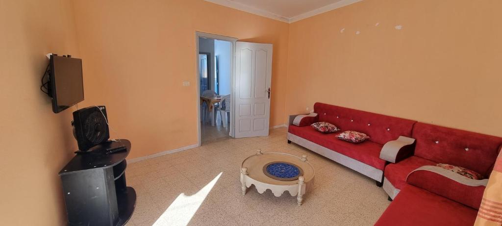 a living room with a red couch and a tv at Appartement meublée à Erriadh in Erriadh