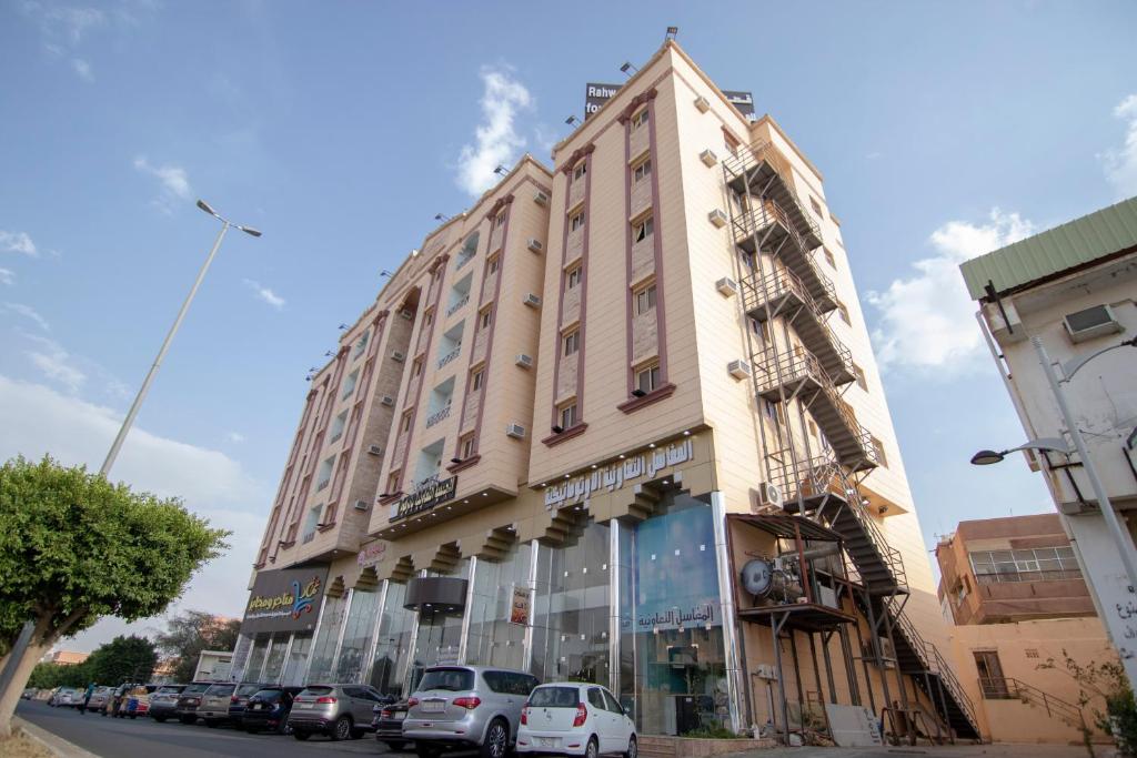 een hoog gebouw met auto's geparkeerd voor het bij قصر رهوان للوحدات الفندقية - Rahwan Palace Hotel Units in Baljurashi