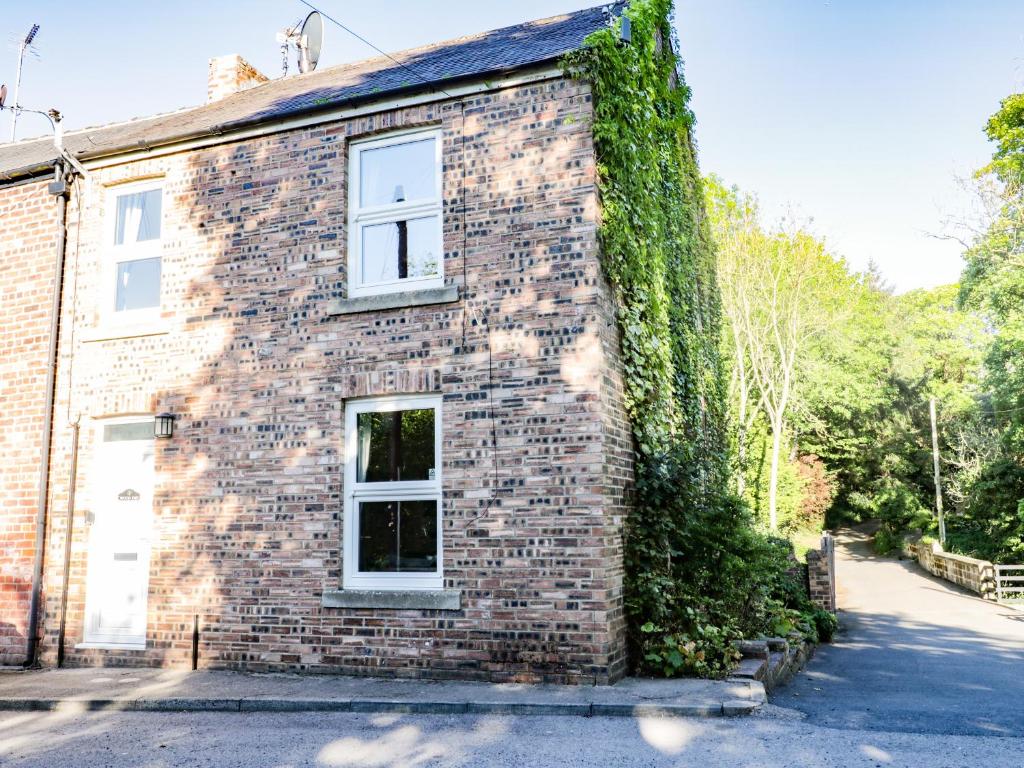 a brick house with a window and ivy at Woodend in Saltburn-by-the-Sea