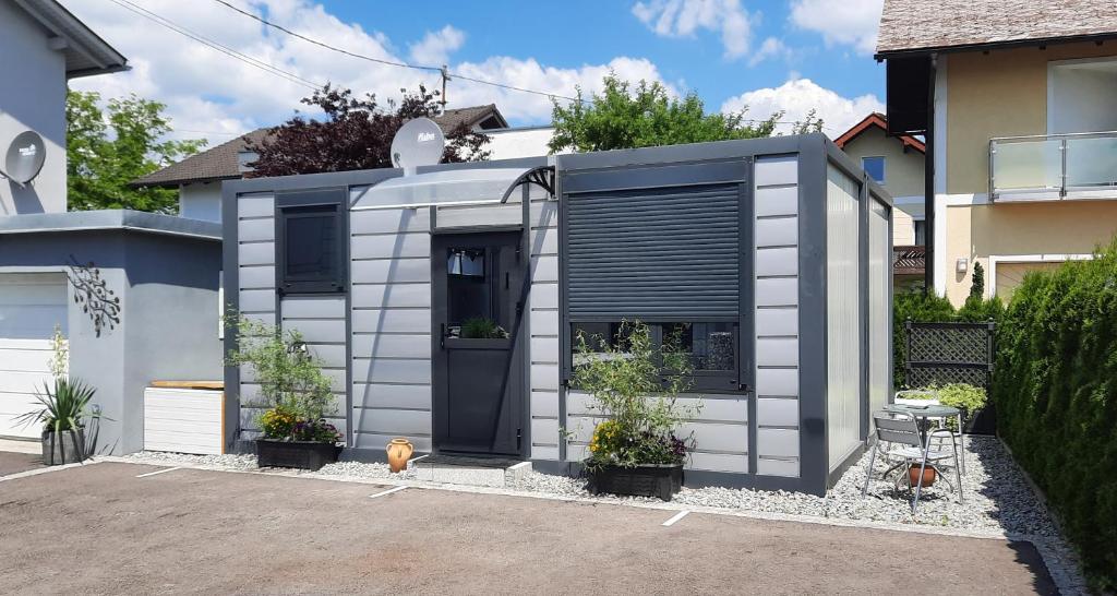 una casa pequeña con una puerta negra y algunas plantas en Gemütliches Tiny Home mit 30m2 inklusive Kochmöglichkeit, en Lenzing