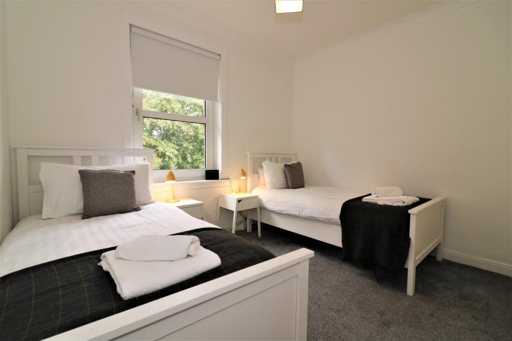 a white bedroom with two beds and a window at Signature - Shawburn House in Hamilton