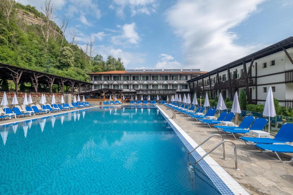 a large swimming pool with chairs and umbrellas at Park Hotel Asenevtsi in Veliko Tŭrnovo