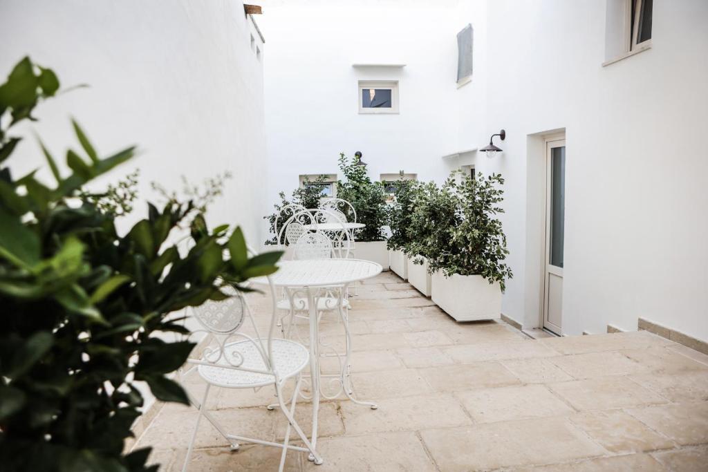 a patio with white tables and chairs and plants at B&B LE DUE CORTI in Matino