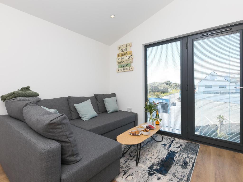 a living room with a gray couch and a table at The Sandbox in Hayle