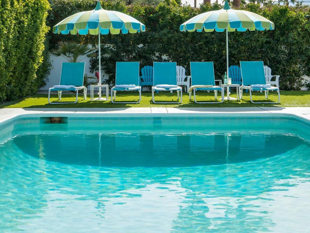 a group of chairs and umbrellas next to a pool at Alexander on Bedford in Palm Springs