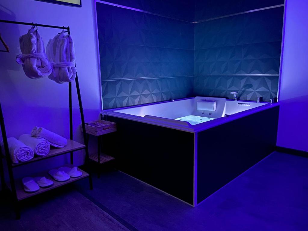 a purple bathroom with a tub and a sink at Privilège Spa, jacuzzi & Sauna 