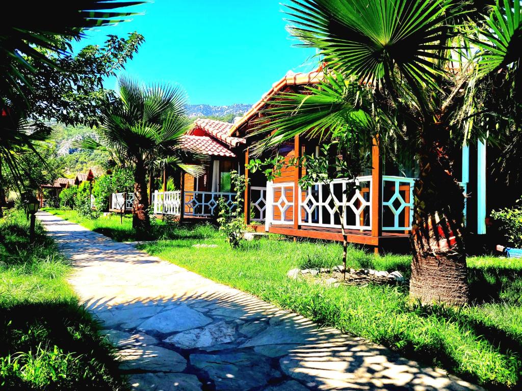 a house with palm trees next to a road at Villa Efsane Hotel in Cıralı