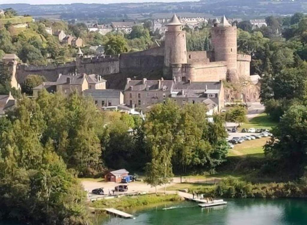 um castelo numa colina ao lado de um corpo de água em Le petit nid du Mont Saint Michel em Pontorson
