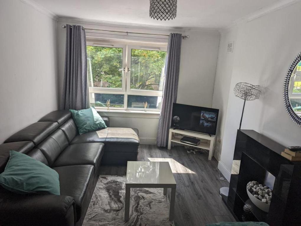 salon ze skórzaną kanapą i telewizorem w obiekcie Central 1-Bed Apt Sleeps 4 5 mins to Station w mieście Greenock