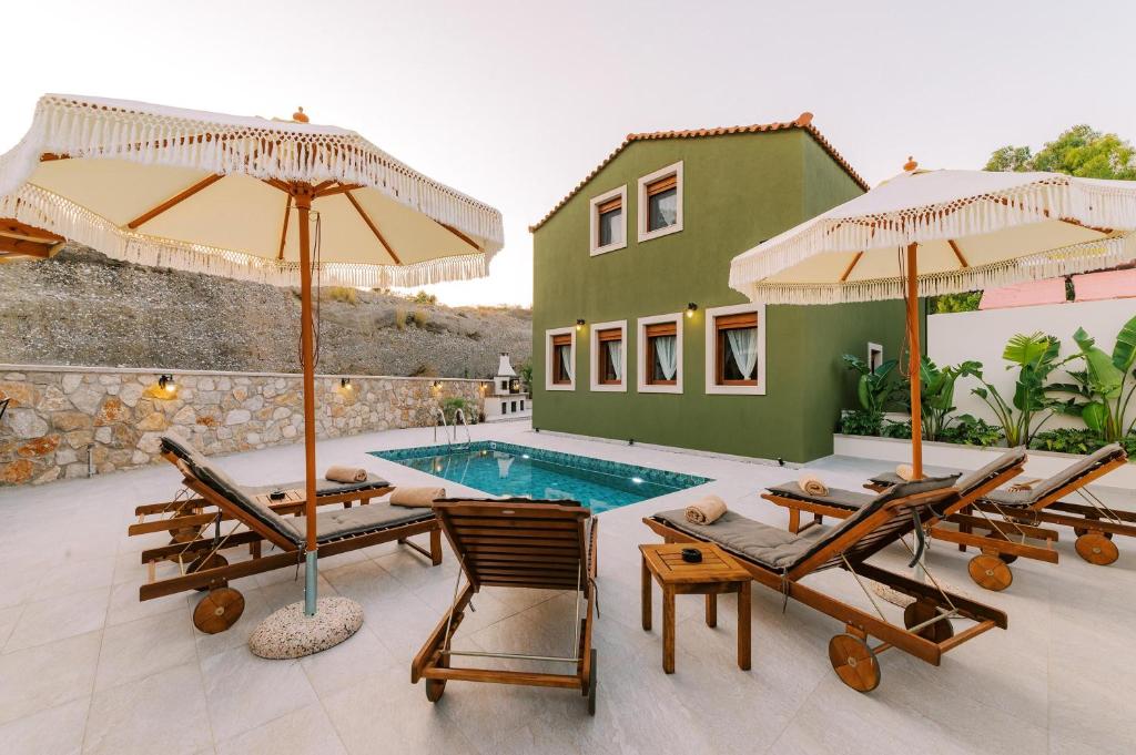 a villa with a swimming pool with chairs and umbrellas at Stavlos Luxury Stone House in Ialysos