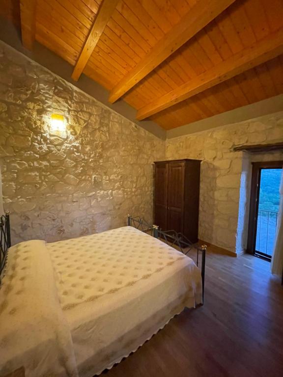 a bedroom with a large bed in a stone wall at La casa di Zio Donato in Roccamorice