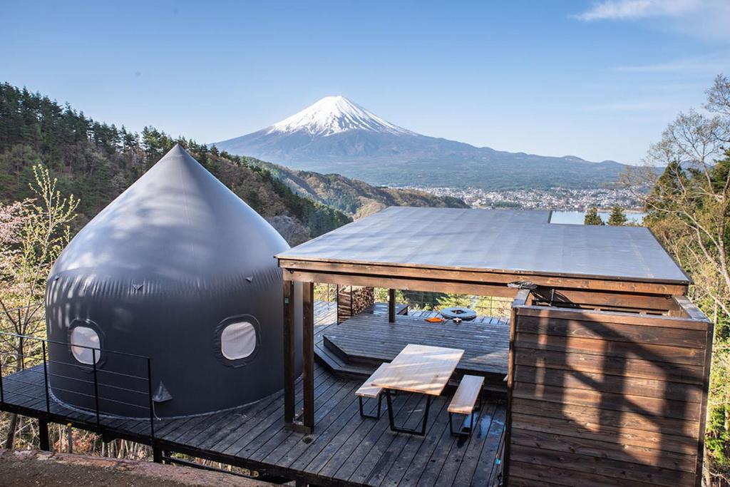 ein Kuppelhaus auf einem Deck mit einem Berg im Hintergrund in der Unterkunft つながるキャンプリゾートQOONEL+ in Azagawa