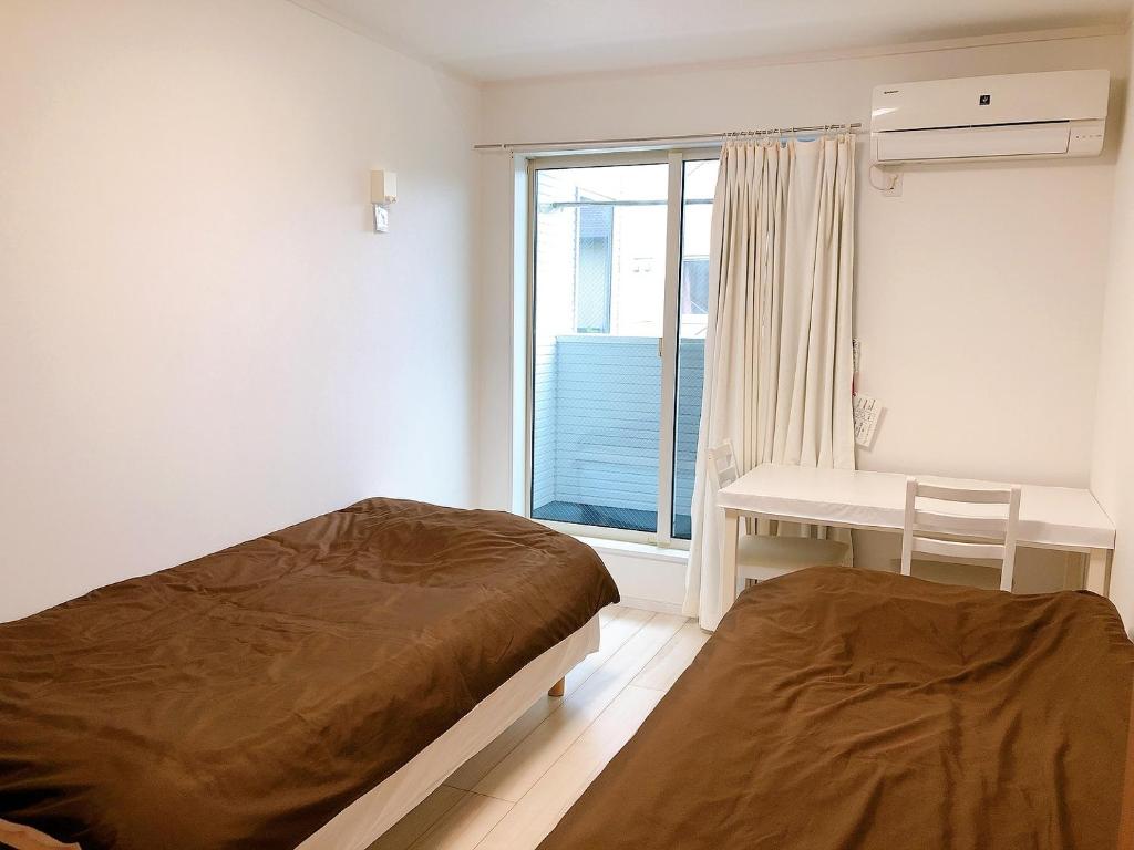 镰仓市Ano House 女性専用Women's Guesthouse的一间卧室设有两张床、一张桌子和一个窗口。