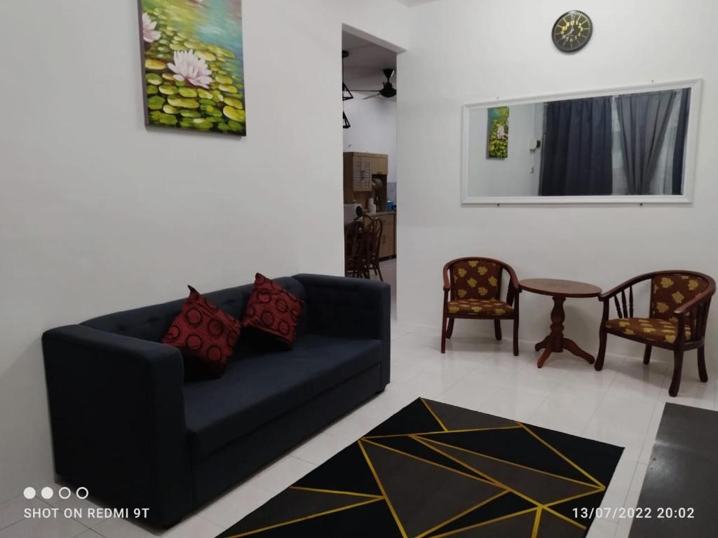 a living room with a blue couch and two chairs at Adempuri homestay in Jitra