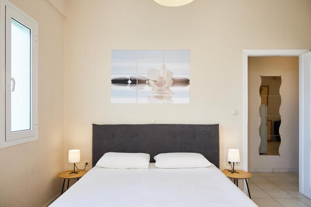 een slaapkamer met een groot wit bed met 2 lampen bij Paralia Vergas Apartments in Verga Kalamata