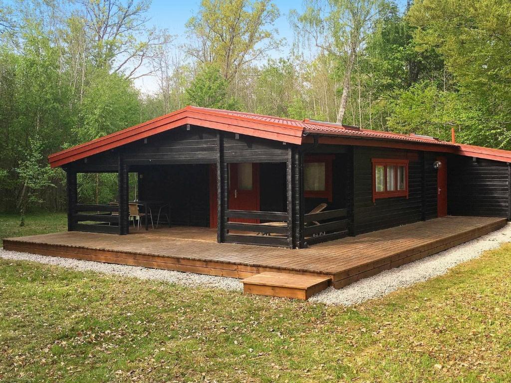 a small cabin with a wooden deck in a field at 4 person holiday home in TYRINGE in Tyringe
