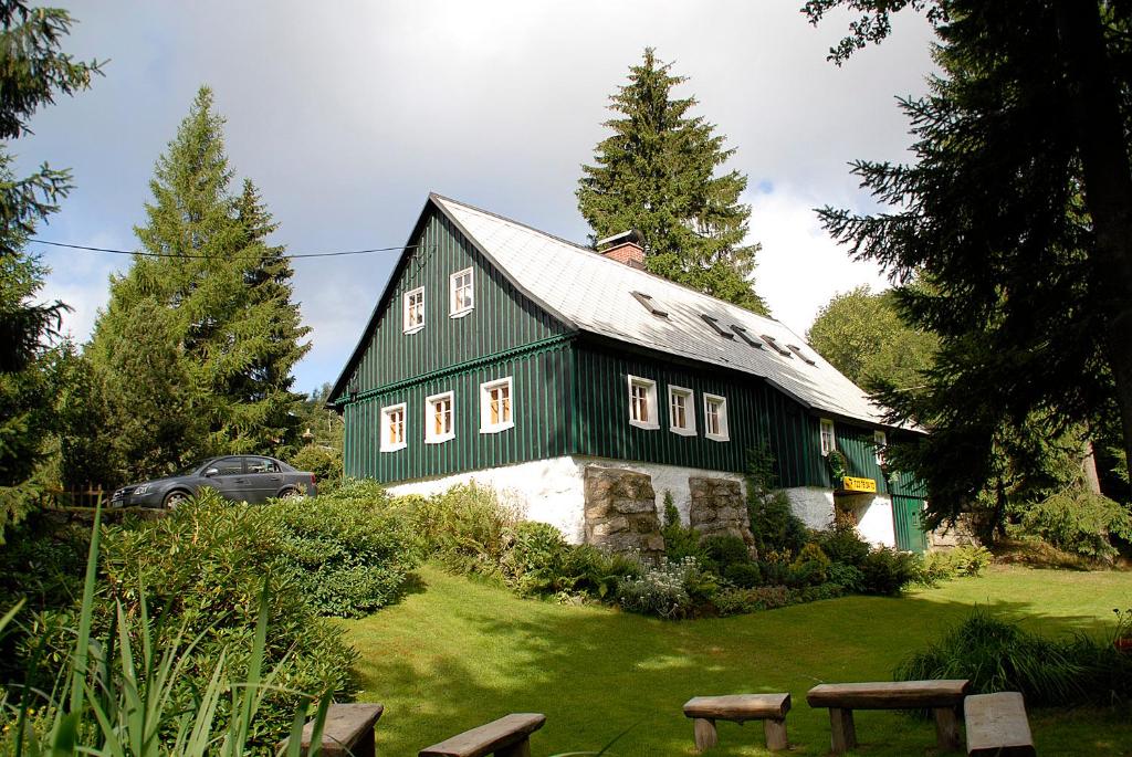 a green and white barn with a car parked next to it at Chalupa Bedřichov in Bedřichov