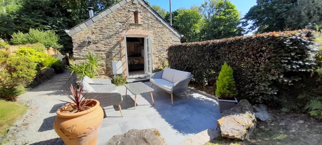 un jardín con un edificio de piedra y un patio en Stunning cosy barn in peaceful rural Cornwall, en Truro