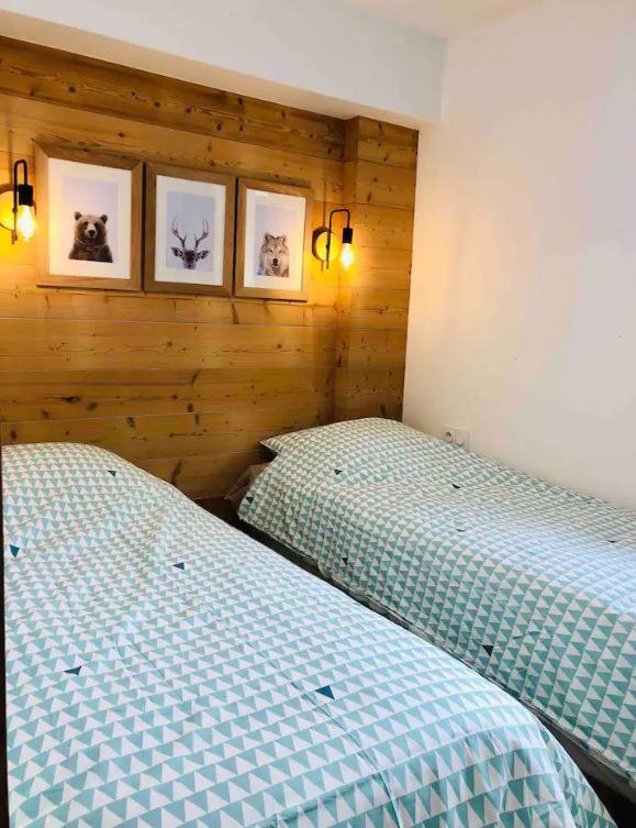 2 łóżka pojedyncze w sypialni z 2 zdjęciami na ścianie w obiekcie Appartement T4 8 couchages spacieux et cosy au pied des pistes w mieście Génos