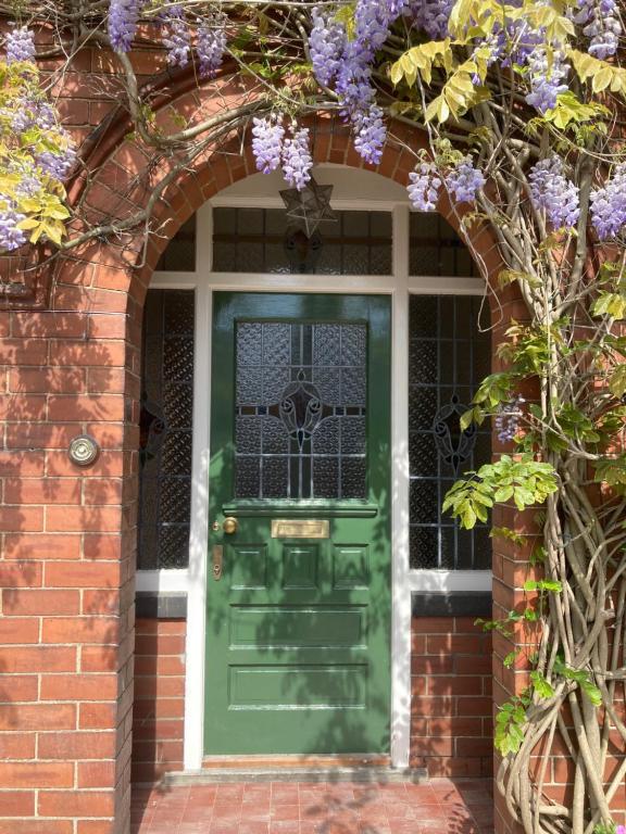 a green door on a brick house with purple flowers at Treblenick House in Thirsk