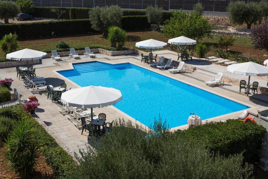an overhead view of a swimming pool with chairs and umbrellas at Hotel Ramapendula in Alberobello